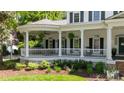 Inviting wraparound porch with white columns, railings, and lush landscaping at 18705 Harbor Light Blvd, Cornelius, NC 28031