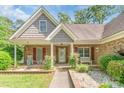 Inviting front porch with brick accents, classic rocking chairs, and a cozy bench seating area at 2020 Olde Towne Dr, Monroe, NC 28110