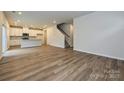 Open-concept living room with stairs and view of kitchen, showcasing hardwood floors at 2206 Silverbell Ln, Stanley, NC 28164