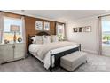 Bedroom featuring large windows, patterned accent wall, and a cushioned bench at the foot of the bed at 4229 Summit Woods Dr, Charlotte, NC 28216