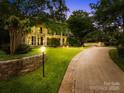Exterior shot of a home with lush landscaping, outdoor lighting and a circular driveway at 4523 Fox Brook Ln, Charlotte, NC 28211