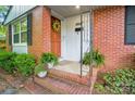 Inviting brick porch with a decorative wreath and potted plants near the home's entrance at 4647 General Pershing Dr, Charlotte, NC 28209