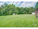 Expansive backyard featuring a lush green lawn, mature trees, and storage sheds at 6573 Weldon Nw Cir # 22, Concord, NC 28027