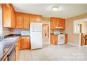 Functional kitchen with wood cabinets, tiled floor, white appliances, and ample counter space at 6573 Weldon Nw Cir # 22, Concord, NC 28027