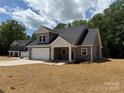 Gray vinyl sided new construction home with a two-car garage, rock accents and freshly seeded yard at 908 Westminster Dr, Statesville, NC 28677