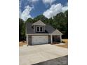 New construction home with a two-car garage, stone accents, and a cozy front porch area at 908 Westminster Dr, Statesville, NC 28677