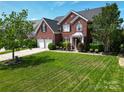 A stately brick home boasts a lush lawn, mature trees, and a welcoming front entrance at 9612 Indian Beech Nw Ave # 1266, Concord, NC 28027