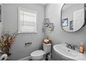 Stylish half bathroom featuring modern fixtures, decorative shelves, and a sleek oval mirror at 10418 Cullen Ct, Charlotte, NC 28278
