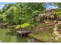 Beautiful backyard with a waterfront view, a wooden dock, and a cozy fire pit area at 141 Ridge Top Rd, Mooresville, NC 28117