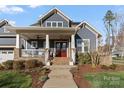 Charming home showcasing a brick walkway leading up to a covered porch with a red front door at 1502 Matthew Mcclure Cir, Davidson, NC 28036