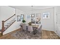 Bright dining area with a wooden table, gray chairs, modern mirrors, and a staircase at 15926 Parkside Crossing Dr # 322, Charlotte, NC 28273