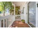 View of the covered porch featuring wood flooring, a glass door, and cheerful hanging floral arrangements at 2109 Brewton Dr, Charlotte, NC 28206