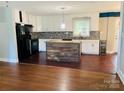 Bright kitchen featuring white cabinets, black appliances, a central island, and hardwood floors at 2823 Albany Ln, Charlotte, NC 28205