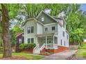 Charming two-story home featuring a covered front porch, complemented by a well-maintained lawn and mature trees at 409 W Kingston Ave, Charlotte, NC 28203