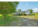 View of the front yard and charming home nestled among mature shade trees at 4122 Canal Rd, Marshville, NC 28103