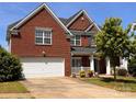 Charming two-story brick home with a well-manicured lawn and attached two-car garage at 6227 Castlecove Rd, Charlotte, NC 28278