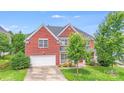 Traditional brick home featuring an attached two-car garage, lush green lawn, and mature trees at 6227 Castlecove Rd, Charlotte, NC 28278