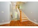 Bright foyer with hardwood floors, a staircase with white railing, and a door to the outside at 6312 Mission Pl, Charlotte, NC 28210
