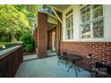 Inviting covered front porch with brick columns, a cozy seating area, and a view of the landscaped yard at 6312 Mission Pl, Charlotte, NC 28210