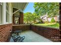 Relaxing covered front porch with brick surround, cozy seating, and a view of the green lawn and landscaping at 6312 Mission Pl, Charlotte, NC 28210