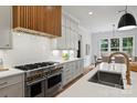 Spacious kitchen featuring stainless steel appliances, a wooden range hood, and an open layout to the dining area at 922 Everett Pl, Charlotte, NC 28205