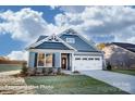 Charming single-Gathering home with blue siding, stone accents, a two-car garage, and manicured lawn at 106 S Inneswood Ln # 31, Mooresville, NC 28115