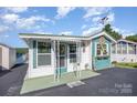 Charming home with teal and white exterior, decorative accents, and delightful curb appeal under a bright blue sky at 125 Maple St, New London, NC 28127