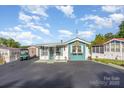 Charming home with teal and white exterior, decorative accents, and a spacious driveway surrounded by lush greenery at 125 Maple St, New London, NC 28127