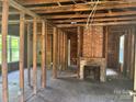 Unfinished living room featuring exposed wood framing and brick fireplace at 126 N Kendall St, Norwood, NC 28128
