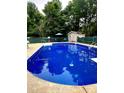 An in-ground pool surrounded by fencing and mature trees with seating area and shed at 128 Paul Snipes Rd, Lancaster, SC 29720
