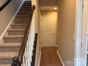 Inviting entryway featuring carpeted stairs, a wooden banister, and durable wood flooring at 13838 Winmau Ln, Huntersville, NC 28078