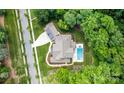 Aerial view of a home showing the roof, pool, well-manicured landscaping, and driveway with surrounding green trees at 17416 Gillican Overlook Rd, Davidson, NC 28036