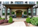 Charming front porch with stone floor, wooden door, plants, and rocking chairs creating an inviting entryway at 17416 Gillican Overlook Rd, Davidson, NC 28036