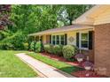Brick ranch style house with beige vinyl siding, dark shutters and lush landscaping at 227 Country Club Cir, Shelby, NC 28150