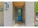 Charming front door with blue finish, brick surround, and stylish outdoor lighting fixture at 2906 Hillside Springs Dr, Charlotte, NC 28209