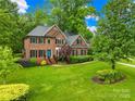 Classic brick home featuring a lush green lawn, mature trees, and a welcoming blue front door at 4339 Shannamara Dr, Matthews, NC 28104