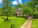 Attractive brick residence with a manicured lawn, mature trees, and a long driveway leading to the house at 4339 Shannamara Dr, Matthews, NC 28104