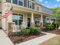 Inviting front porch with rocking chairs, lush landscaping, American flag and beautiful columns at 5013 Hamilton Mill Dr, Waxhaw, NC 28173