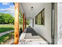 Spacious covered front porch with natural wood columns, black trim and painted brick at 5428 Barnsdale Ln, Mint Hill, NC 28227