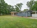 Well-maintained single-story home with a stone porch, side carport, and lush green lawn at 6604 Plyler Mill Rd, Monroe, NC 28112