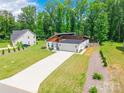 Aerial view of modern home, large front yard, with a long driveway and wooded area surrounding it at 7728 Shalom Dr, Charlotte, NC 28216