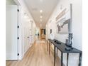 Long hallway with wood-look flooring, white walls, and a decorative table with accessories at 7728 Shalom Dr, Charlotte, NC 28216