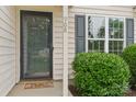 Close-up of the front door and window with black shutters, complemented by manicured shrubbery at 908 Dairy Meadow Ct, Monroe, NC 28110