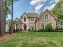 Charming brick home featuring a manicured front lawn and mature trees at 10924 Lederer Ave, Charlotte, NC 28277