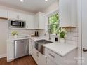 Modern kitchen featuring white cabinets, stainless steel appliances, and a farmhouse sink with backyard view at 1147 Norland Rd, Charlotte, NC 28205