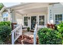 Close-up of the inviting front porch with brick steps, white railings, and a cozy seating area at 17307 Villanova Rd, Huntersville, NC 28078