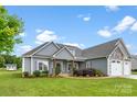 Charming home exterior featuring gray siding, stone accents, well-manicured lawn, and a three car garage at 210 Dorothy Dr, China Grove, NC 28023