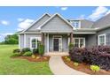 Inviting front porch with stone accents, decorative shrubs, and a black front door with a wreath at 210 Dorothy Dr, China Grove, NC 28023