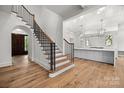 Elegant foyer featuring a staircase with wooden steps and black railings, and a modern, bright kitchen at 2710 Briarcliff Pl, Charlotte, NC 28207