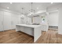 A modern kitchen featuring a large island with sink, white cabinets, stainless steel appliances, and hardwood floors at 2710 Briarcliff Pl, Charlotte, NC 28207